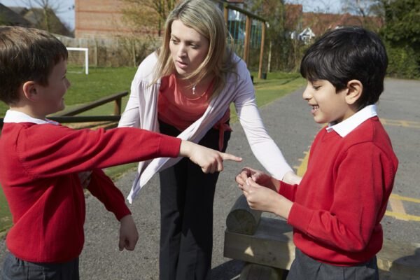 Teacher,Stopping,Two,Boys,Fighting,In,Playground