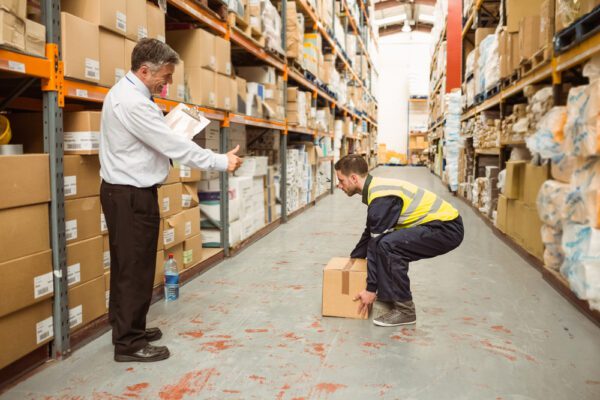 Manager,Watching,Worker,Carrying,Boxes,In,A,Large,Warehouse