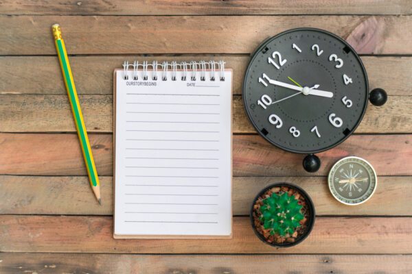 Notepad,With,Pencil,,Notebook,And,Clock,On,Wood,Board,Background.using